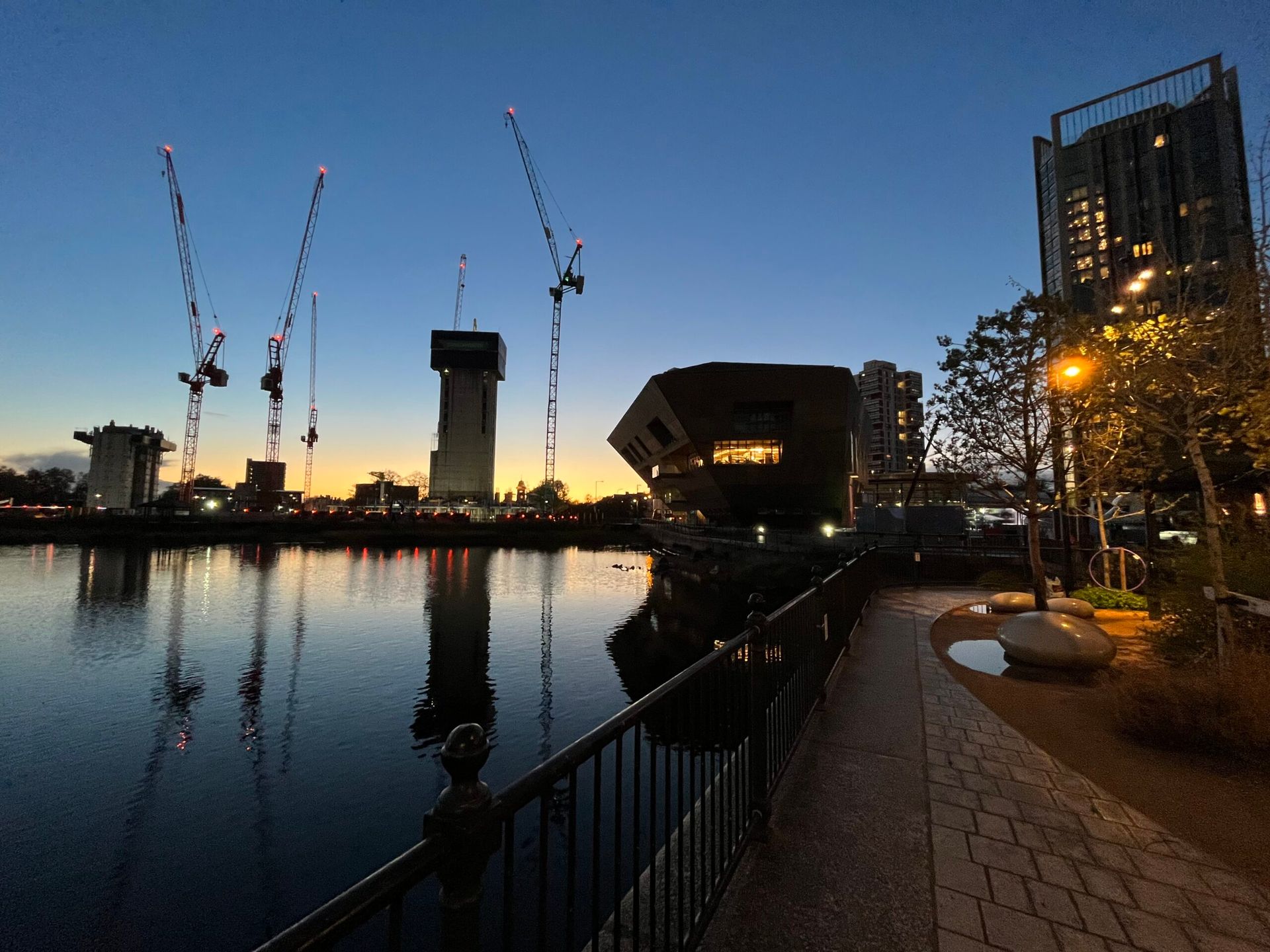 City sunset 🌆over a lake with an hexagonalo/angular/polygon shaped building next to it that looks like the Star Wars sand crawler vehicle for the Houdinis